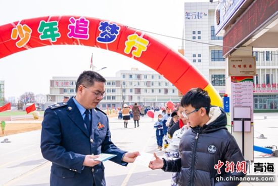 图为税务干部在校门口向同学们发放税法知识宣传册 。杨扬 摄