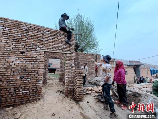 图为曹旦么村村民在建筑队的帮助下修建房屋。李隽 摄