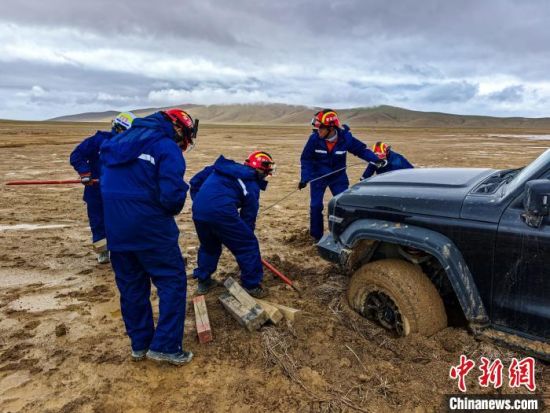 图为消防救援人员正在清理被困车辆轮胎周围淤泥。吴治国摄