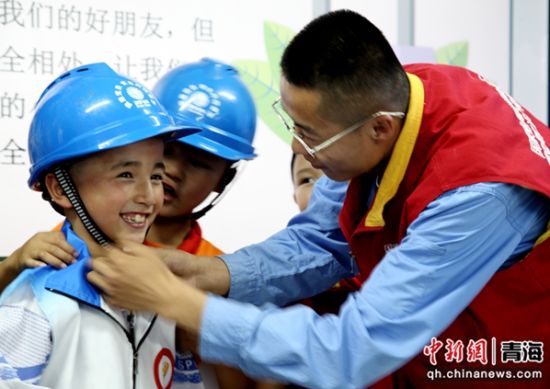 图为9月2日国网同仁市供电公司阿玮电力爱心服务队走进同仁市第一完全小学三年级二班开展安全用电进校园活动，现场为学生示范如何正确佩戴安全帽。祁正吉摄